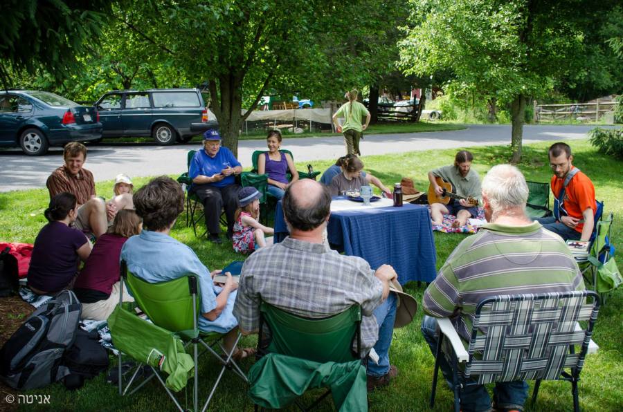 People gathered in a circle to sing together for worship all sitting in lawn chairs